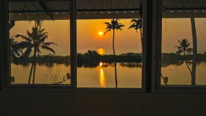 a view of a sunset from a window at Lake Star Beach Resort in Kappil