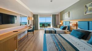 a hotel room with two beds and a desk at Aquasis De Luxe Resort & SPA - Ultra All Inclusive in Didim