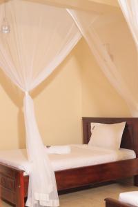 a bedroom with a canopy bed with white curtains at HOIMA KOLPING HOTEL in Hoima