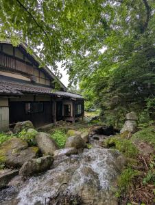 a house and a stream in front of a house at Yamanoto in Toyooka