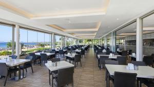 a restaurant with tables and chairs and windows at Aquasis De Luxe Resort & SPA - Ultra All Inclusive in Didim