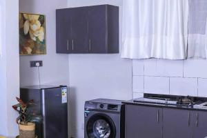 a kitchen with a washing machine and a refrigerator at Elite properties in Kampala