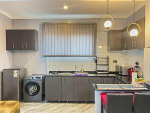 a kitchen with a stove and a washing machine at Elite properties in Kampala