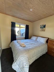 a bedroom with a bed and a window with towels on it at A Gem by the Beach 4 bedroom Abel Tasman in Kaiteriteri