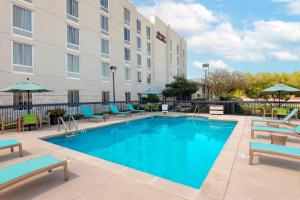 a pool in front of a hotel with chairs and umbrellas at Hampton Inn & Suites-Austin Airport in Austin
