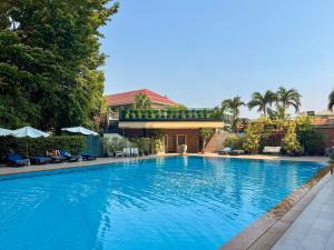 a large swimming pool with trees and a building at Golden Beach Hotel Pattaya in Pattaya