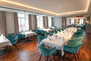 a dining room with white tables and green chairs at Landhaus Hechtsberg in Hausach