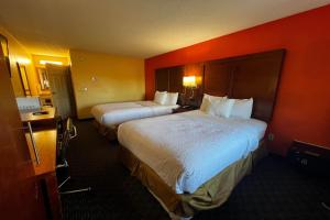 two beds in a hotel room with orange walls at TraveIodge by Wyndham Parsippany in Parsippany