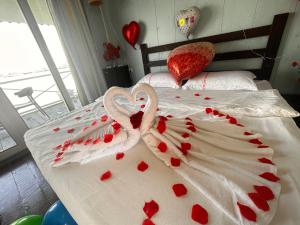 two swans are laying on a bed covered in hearts at 微拉瓦丽 in Semporna