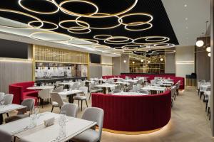 a dining room with white tables and red chairs at Ramada by Wyndham Zalau in Zalău