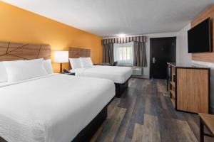 a hotel room with two beds and a flat screen tv at Howard Johnson by Wyndham Malden Boston Area in Malden