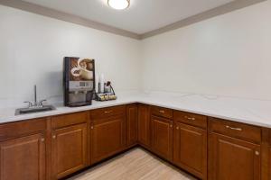 a kitchen with wooden cabinets and a microwave at Howard Johnson by Wyndham Malden Boston Area in Malden