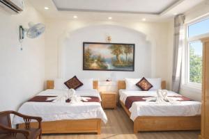 two beds in a room with a painting on the wall at Kim Ngân Hotel Buôn Ma Thuột in Buon Ma Thuot