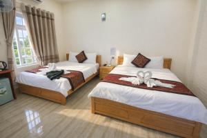 a bedroom with two beds with bows on them at Kim Ngân Hotel Buôn Ma Thuột in Buon Ma Thuot