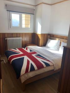 a bedroom with a bed with a red white and blue blanket at CentreToni Arida in Al Arz