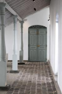 a green door in a white room with columns at Indigaslanda Walawwa in Bopitiya +60 photos
