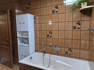 a bath tub in a bathroom with a tile wall at Ferienhaus mit Garten in Traiskirchen