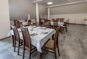 a dining room with white tables and wooden chairs at Ośrodek Wypoczynkowy Caritas in Wałcz