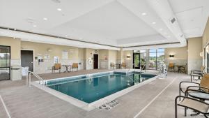 a pool in a hotel with chairs and tables at Hampton Inn & Suites Chippewa Falls in Chippewa Falls