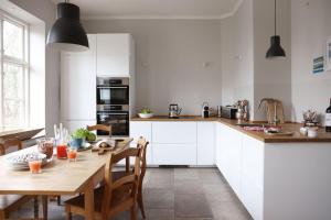 a kitchen with white cabinets and a wooden table at Müllerhaus - Ostholstein in KÃ¶hn