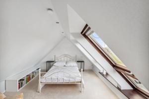 a white bedroom with a bed and a window at Landhaus Köhn - Ostholstein in Giekau
