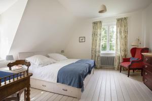 a bedroom with a large bed and a red chair at Pächterhaus - Ostholstein in Manhagen