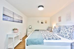 a white bedroom with a bed and a dresser at Ferienhaus Schreieck in Pöcking