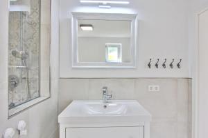 a white bathroom with a sink and a mirror at Ferienhaus Schreieck in Pöcking +16 photos