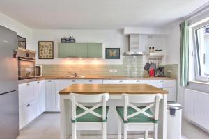 a kitchen with a wooden table and two white stools at Ferienhaus Schreieck in Pöcking