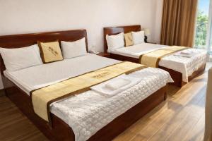 two beds in a hotel room withskirts at Hotel Ngoc Anh - Van Don in Quang Ninh