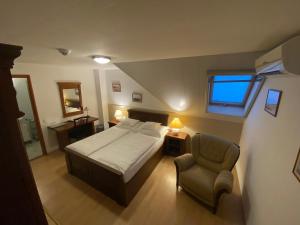 a bedroom with a bed and a chair and a window at Juhász Fogadó in Fonyód