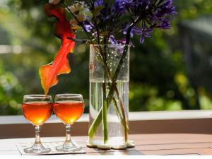 two wine glasses and a vase with flowers on a table at Ceylon Vista in Galle +21 photos