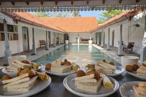 a table with plates of food next to a swimming pool at Indigaslanda Walawwa in Bopitiya