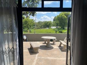 a patio with a table and benches outside a window at Rapids View Cottage in Parys