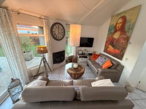 a living room with a couch and a clock on the wall at Ferienhaus am Meer mit Kamin & Sauna - Seestern 251 in Julianadorp