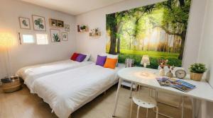 two beds in a room with a table and a painting at Marine Mini House in Busan
