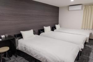 zwei Betten in einem Hotelzimmer mit weißer Bettwäsche in der Unterkunft HOTEL STAY Plus in Imabari + 7 Fotos