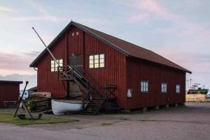 a large red barn with a boat next to it at Hus nära havet in Bergkvara