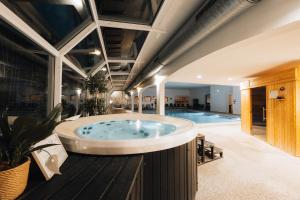 ein großes Badezimmer mit Whirlpool und Swimmingpool in der Unterkunft Hôtel Causse Comtal Rodez, The Originals Relais in Gages-le-Haut