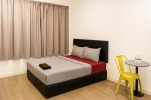 a bedroom with a bed with a table and a yellow chair at Intime Hotel Kuchai Lama Kuala Lumpur in Kuala Lumpur