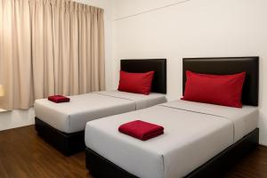 two beds with red pillows in a room at Intime Hotel Kuchai Lama Kuala Lumpur in Kuala Lumpur