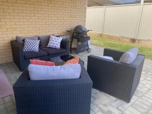 two wicker chairs and a couch with pillows on a patio at Grand stay in Perth