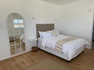 a white bedroom with a bed and a mirror at Old Harbour Place in Gansbaai +16 photos