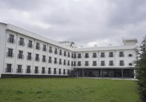 a large white building with a grass field in front of it at Sakarya Hotel in Sakarya