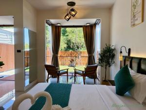 a bedroom with a bed and chairs and a large window at มนต์จันทรา เฮ้าส์ in Khlong Lan