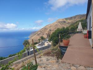 a house with a wooden walkway next to the ocean at Farol views in Fajã da Ovelha +12 photos