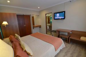 ein Schlafzimmer mit einem Bett und einem TV an der Wand in der Unterkunft Alto Verde Suite & Apart in Termas de Río Hondo