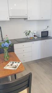 a kitchen with white cabinets and a wooden table at Farol views in Fajã da Ovelha