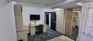 ein Zimmer mit einem Schreibtisch, auf dem ein Computer und ein Fernseher stehen in der Unterkunft Hotel Rapsodia City Center in Botoşani