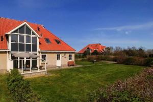 a house with an orange roof and a yard at Waddenvilla 7 in Hollum
